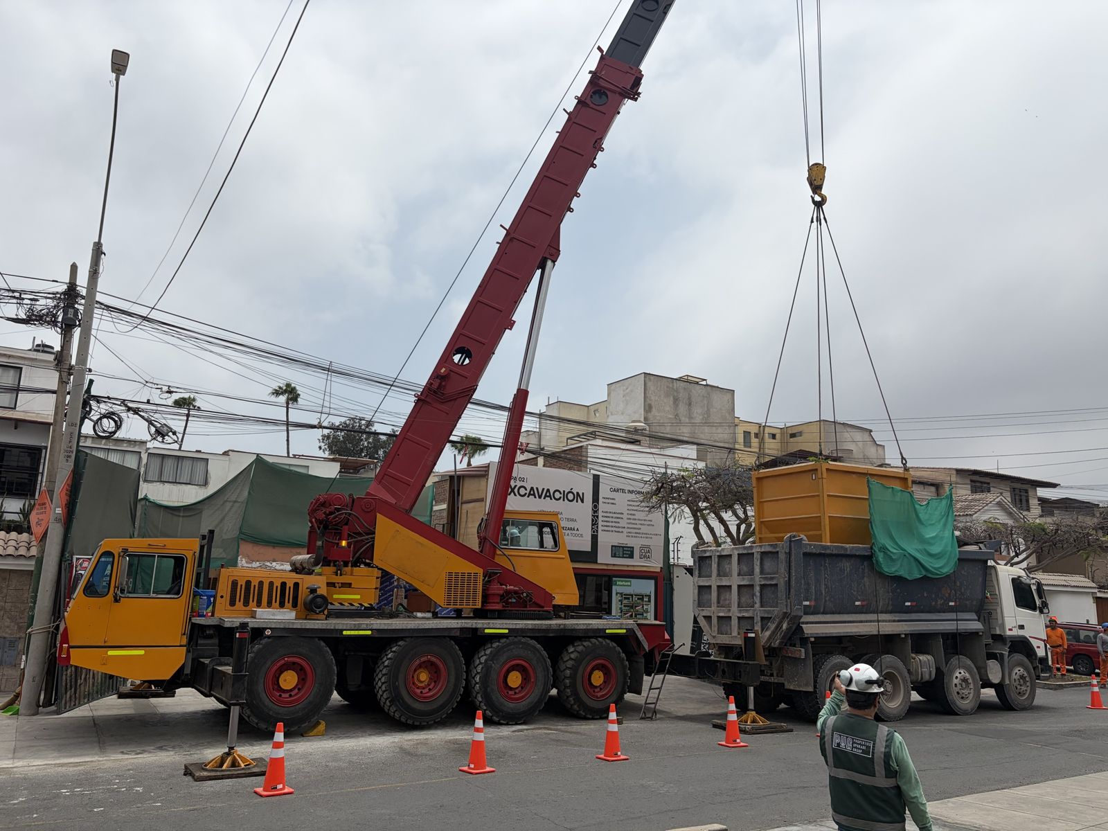 Grúa de Ememca descargando un balde de tierra sobre un volquete