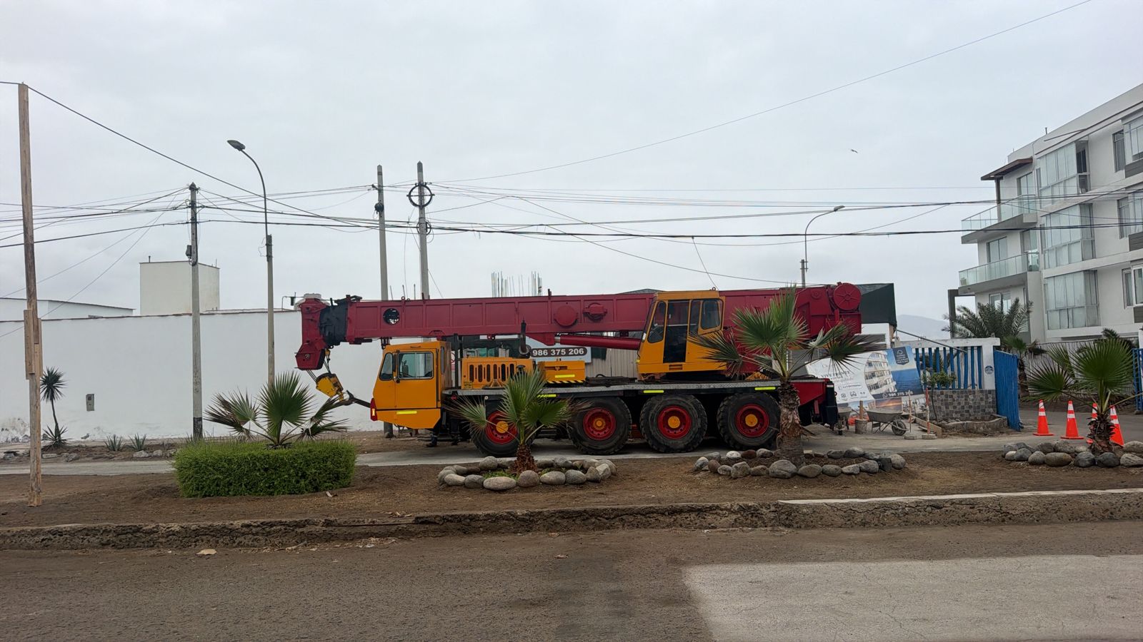 Grúa telescópica de Ememca estacionada frente a una obra