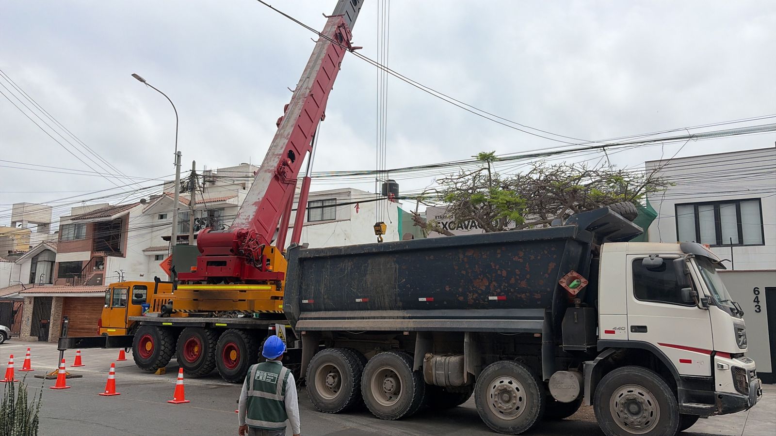 Grúa de Ememca cargando un volquete en una obra de excavación