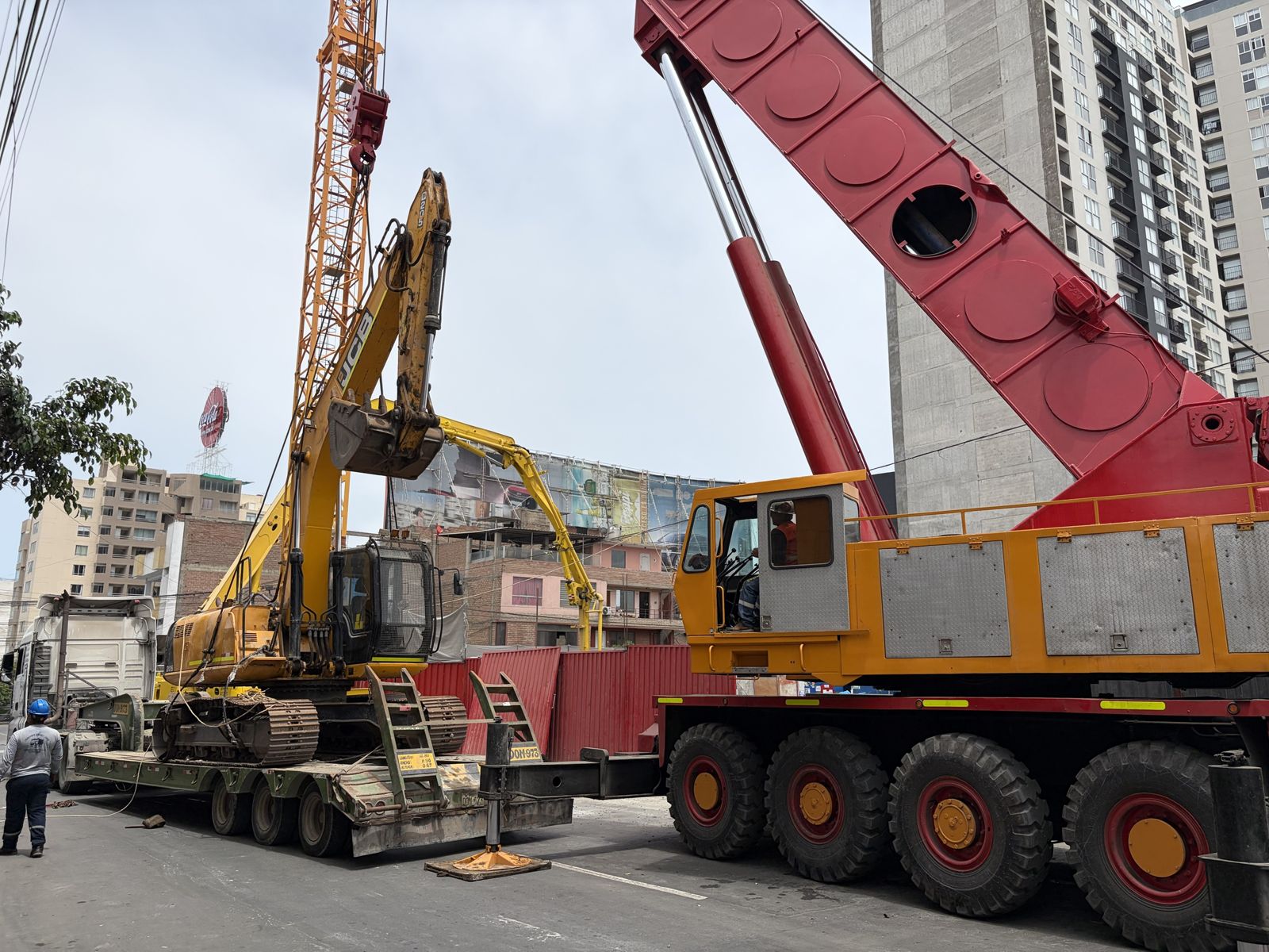 Excavadora JCB cargada en cama baja junto a la grúa de Ememca